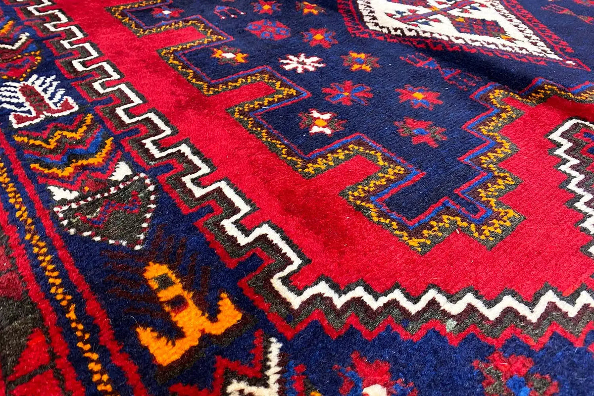Oriental rug with red areas, a deep blue background, and multicolored borders.