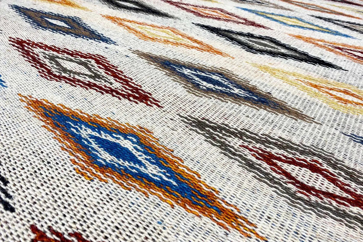 Kilim dhurrie rug with a geometric pattern in blue, red, and orange on a light background
