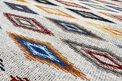 Kilim dhurrie rug with a geometric pattern in blue, red, and orange on a light background