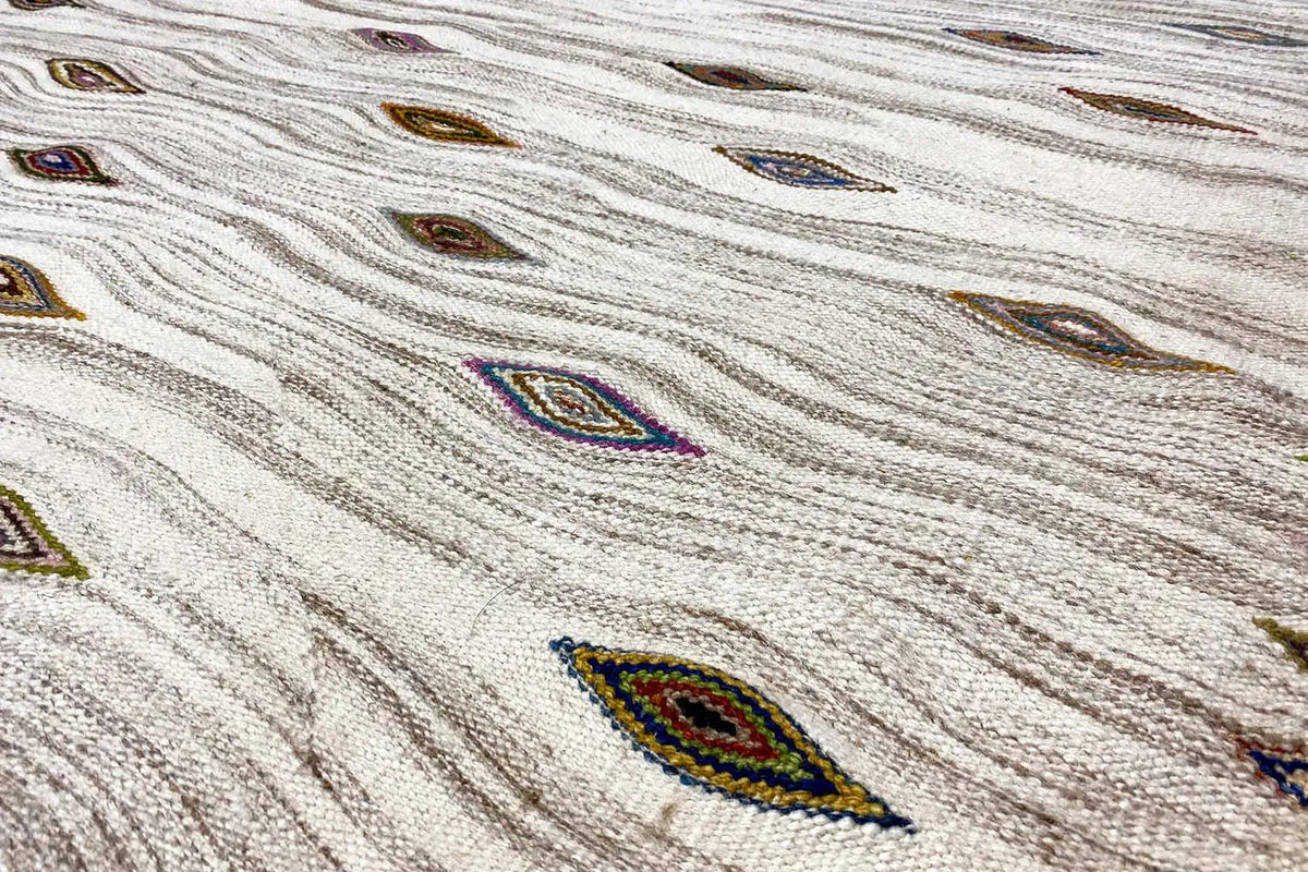 Close-up of a cream kilim-dhurrie rug with multicolored diamonds