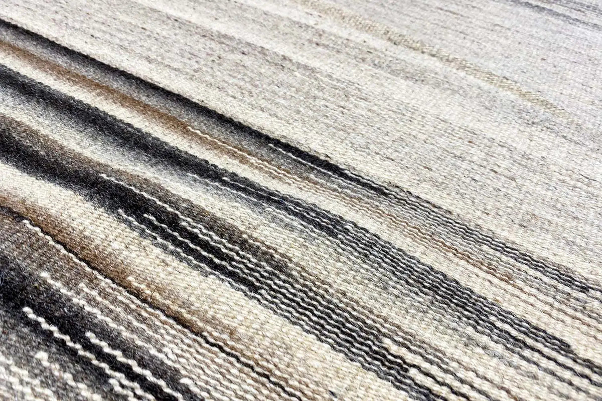 Dhurrie rug: close-up with a striped pattern in gray and brown on a light background