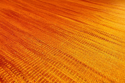 Yellow-orange kilim rug with a fine woven pattern, close-up of the surface