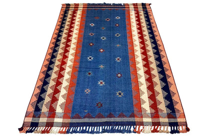 Rectangular rug with a blue center, a red-and-white zigzag stripe pattern, and fringes