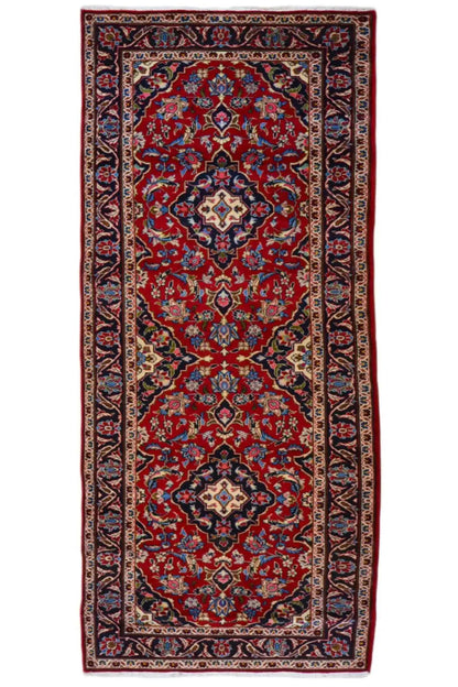 Rectangular Oriental rug with a red field, blue-red medallions, and decorative border.