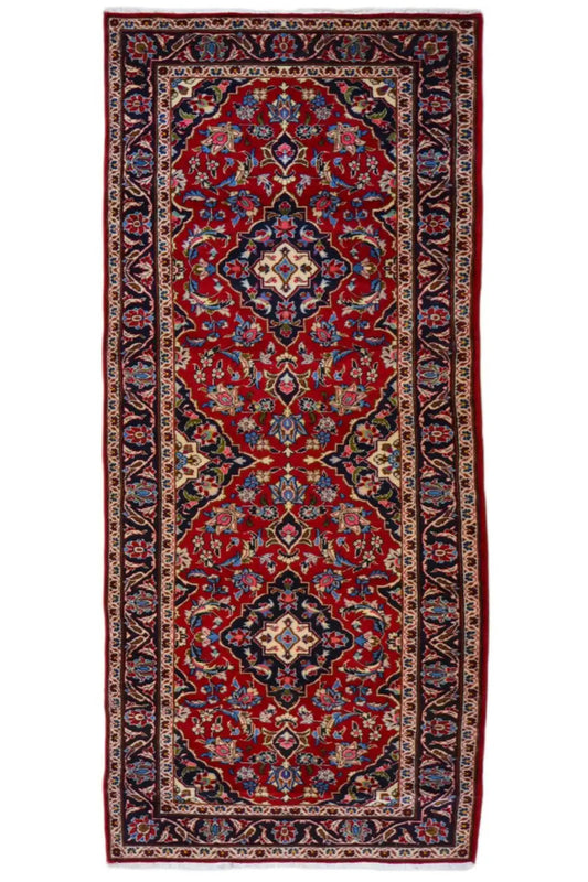 Rectangular Oriental rug with a red field, blue-red medallions, and decorative border.