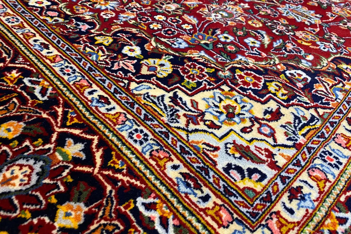 Close-up of a Keshan rug with colorful ornamental borders in red, blue, and yellow