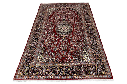Keshan rug, burgundy field with a light medallion, surrounding ornamental border in dark blue.