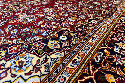 Close-up of a Keshan rug: colorful floral patterns in blue, red, and green along the edge.