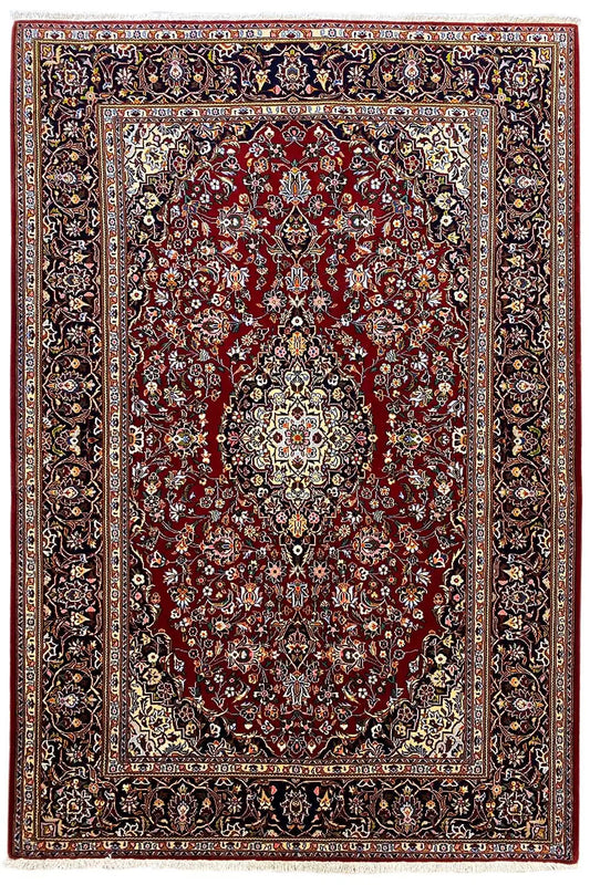 Keshan rug with a red field, central medallion, and wide dark patterned border.