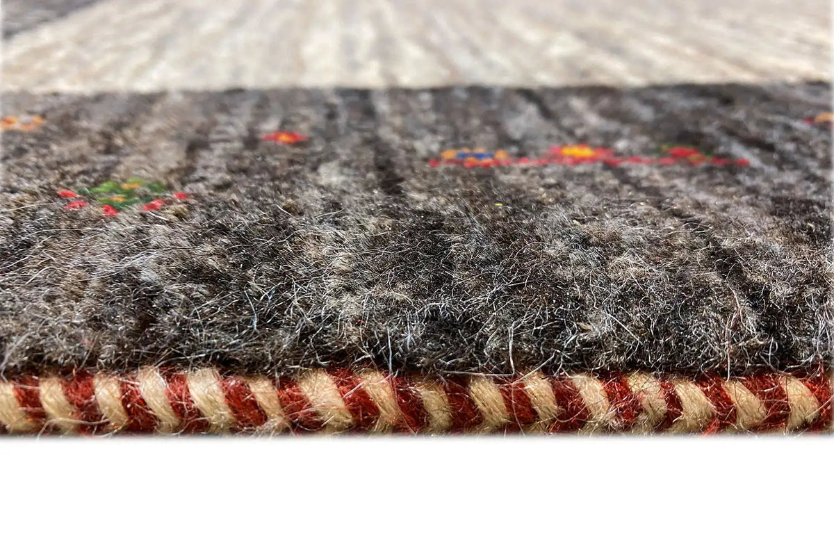 Gabbeh rug edge detail with fringed finish and dark border trim