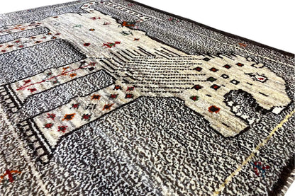 Close-up of a Gabbeh rug: gray textured pile, cream pattern, small red ornaments