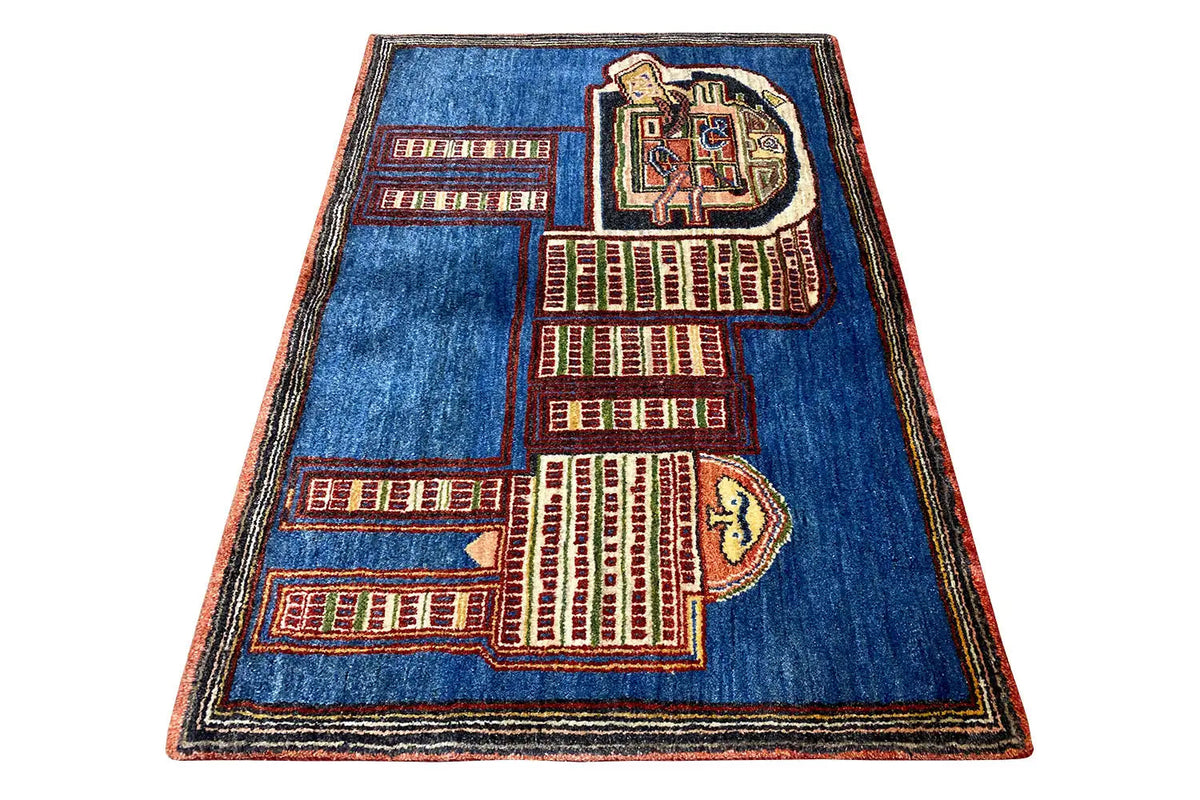 Blue Gabbeh rug spread at an angle with a red and beige city and lion pattern