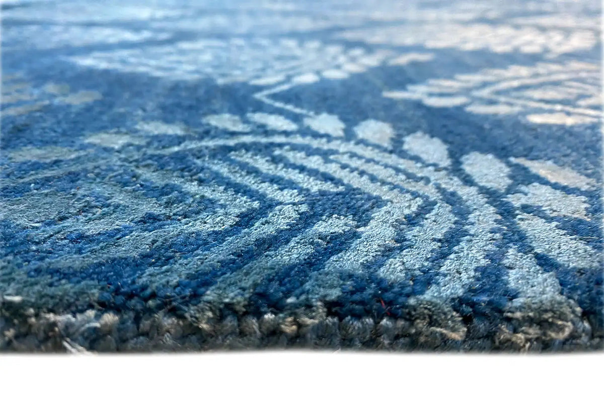 Designer rug close-up: blue pile with a light pattern and a border all around