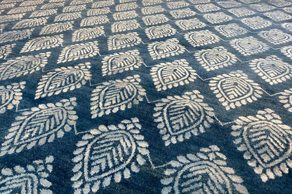 Designer rug close-up: blue ornamental pattern with cream-colored details, pile visible
