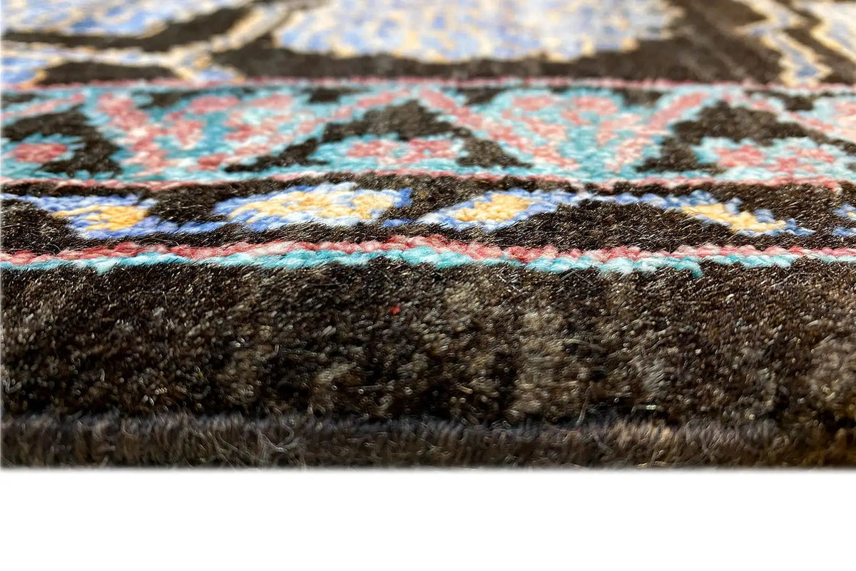 Carpet edge with a blue pattern in the pile and a dark backing, close-up of the edge