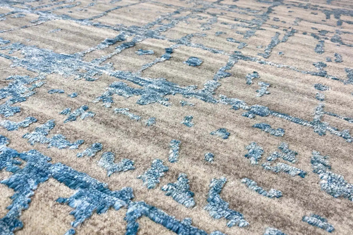 Detail of the rug: beige pile with a blue ornamental element and woven texture