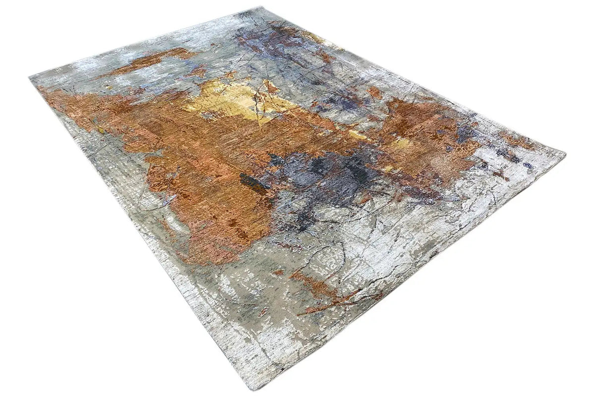 Designer rug in angled view: abstract pattern in shades of brown, blue, and gray
