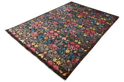 Designer rug from an angled view: colorful floral ornament on a dark gray background