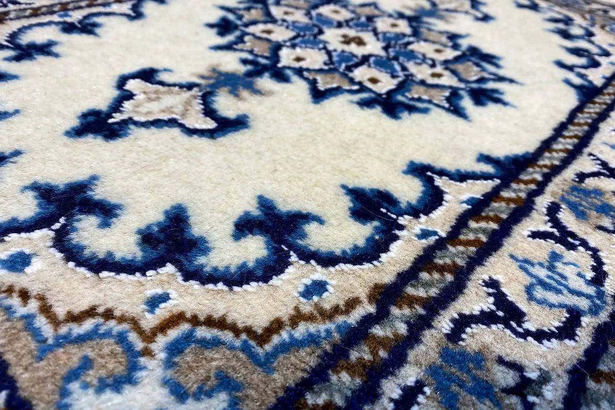 Close-up of a blue ornament on a beige Nain rug with fine borders