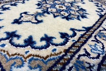 Close-up of a blue ornament on a beige Nain rug with fine borders