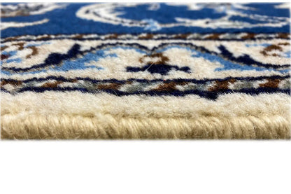 Close-up of a rug edge with fringe, a blue-and-white pattern, and beige pile
