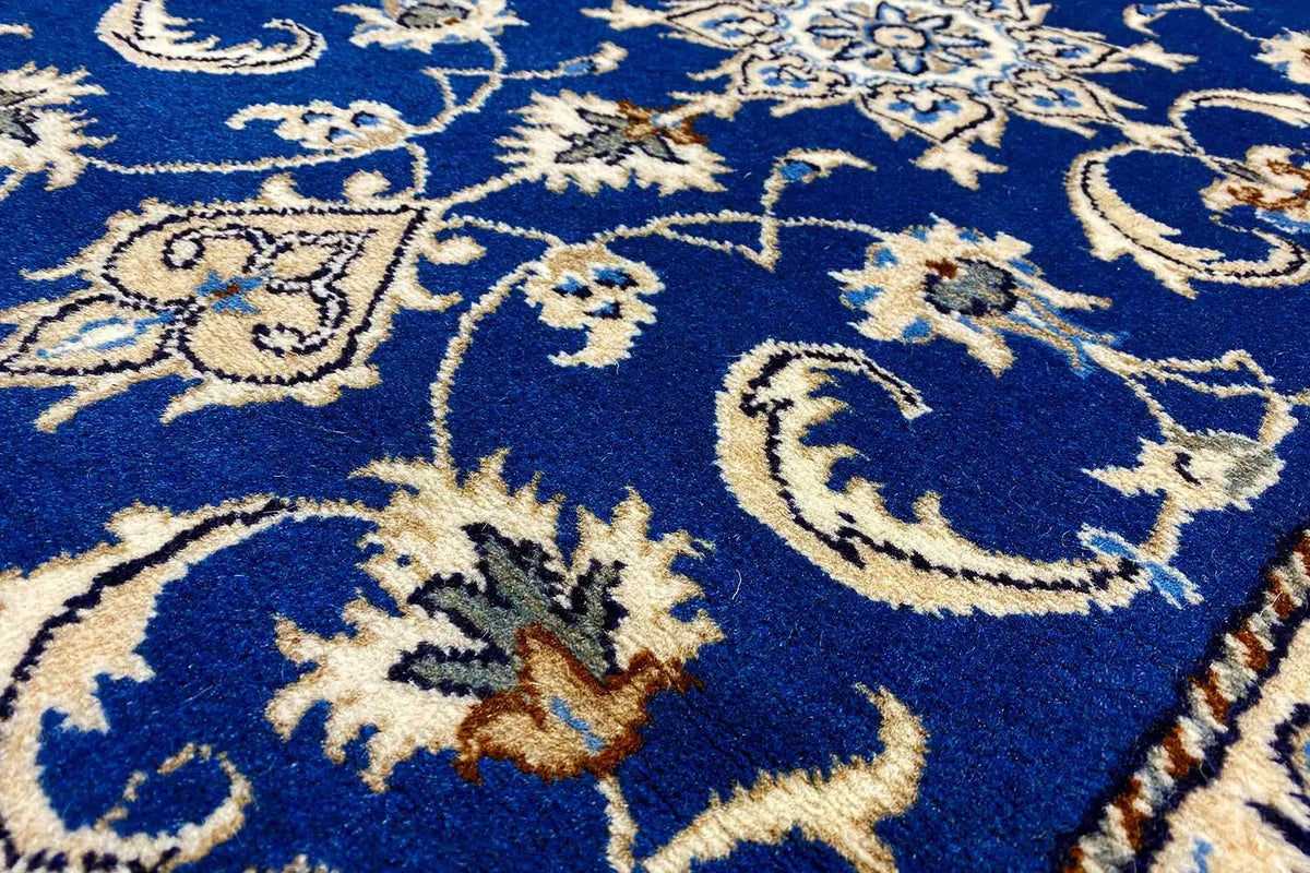 Close-up: blue carpet fabric with gold-and-white floral ornaments and vines