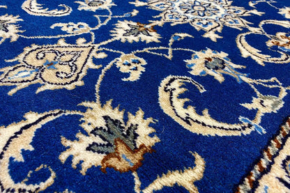 Close-up: blue carpet fabric with gold-and-white floral ornaments and vines