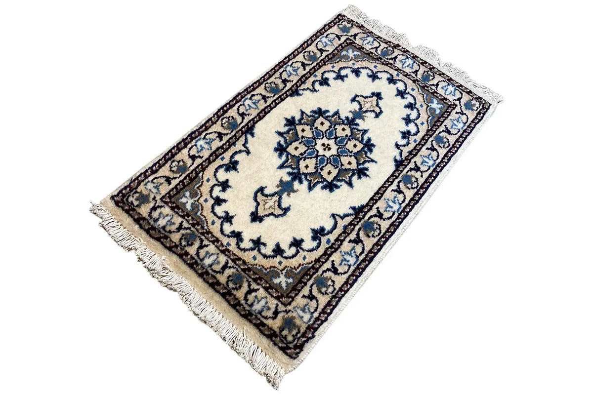 Oriental rug 65x38 cm shown at an angle with a blue-and-white medallion pattern and fringes