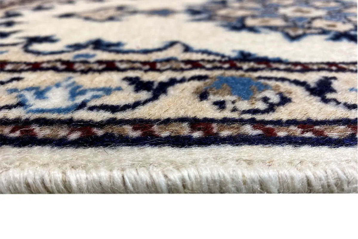 Carpet edge with white fringes and a blue border pattern, close-up