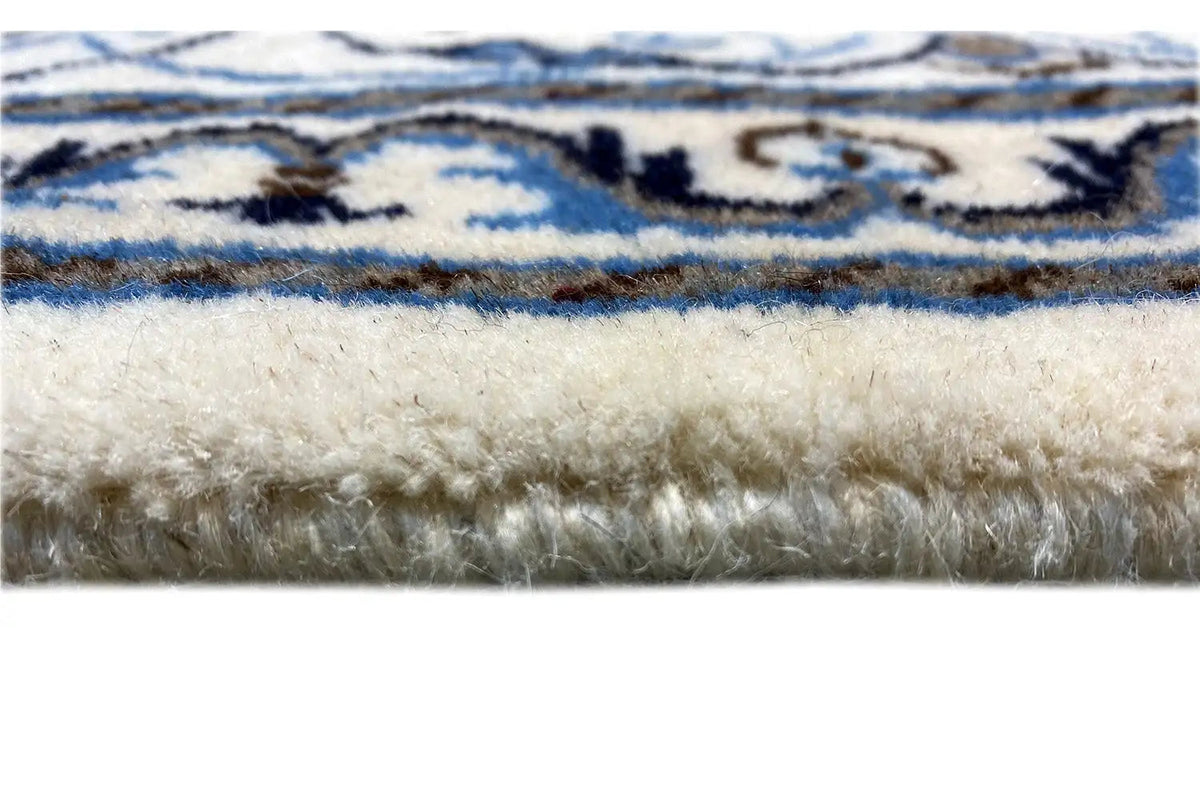 Carpet fringe at the edge, blue-and-white border and floral pattern, textured wool