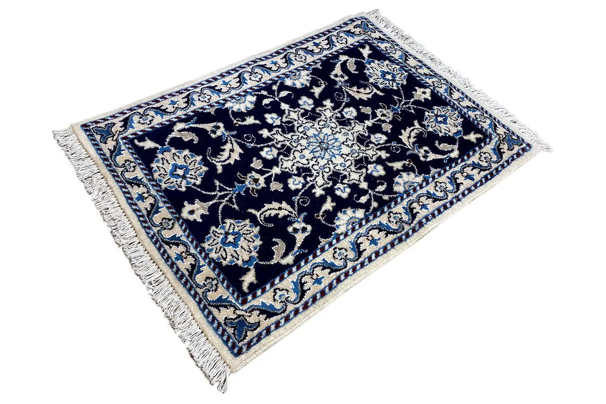 Nain rug 90x61 cm, photographed at an angle, with fringes and light blue details in the pattern