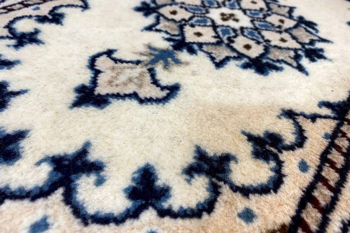 Close-up of Nain rug (65x39 cm): cream-colored surface with a blue pattern