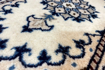 Close-up of Nain rug (65x39 cm): cream-colored surface with a blue pattern