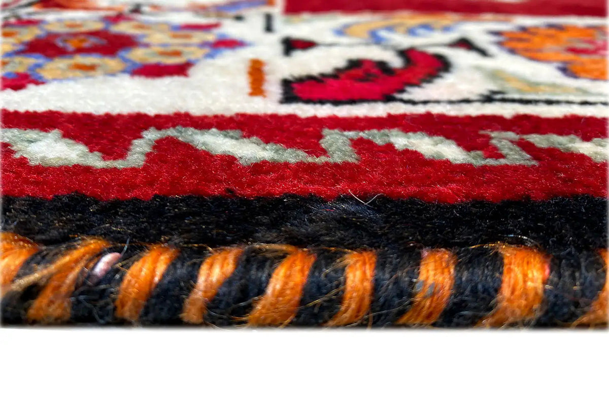 Carpet fringes and finely woven border in red, black, and blue, detail view
