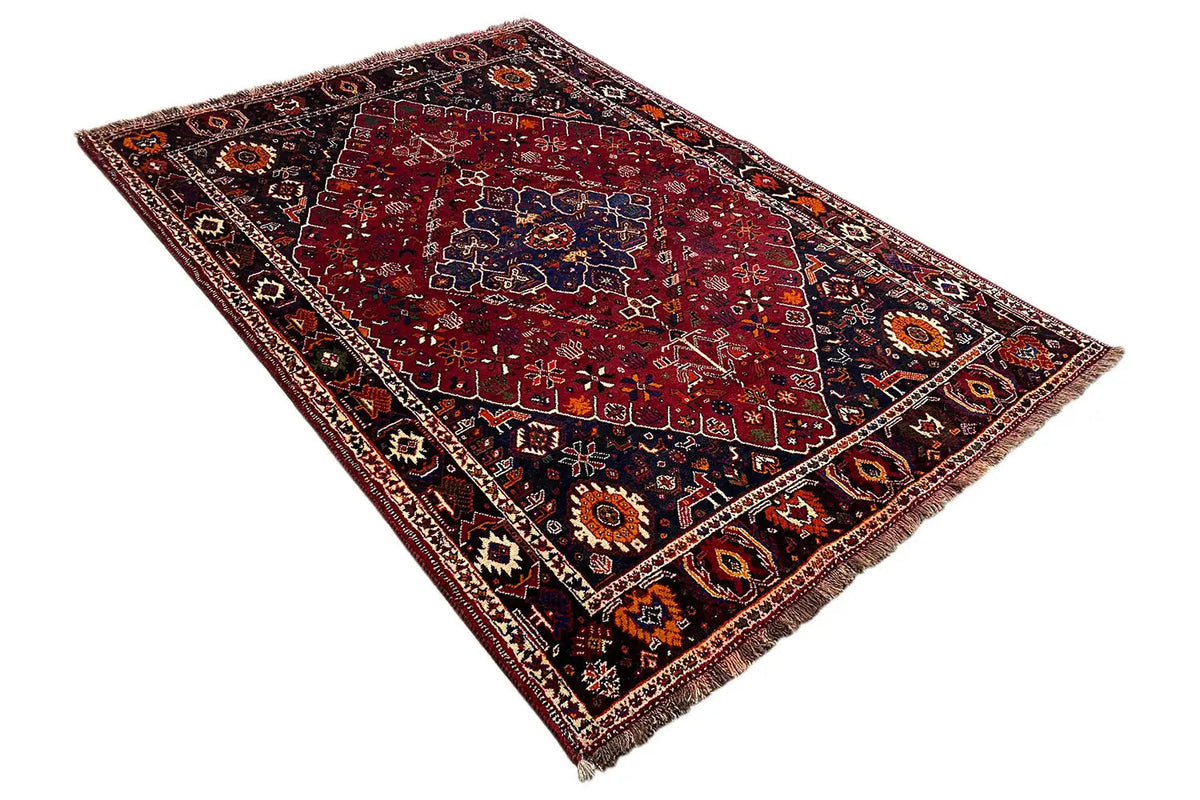Oriental rug at an angle, red medallion pattern with multicolored border and fringes