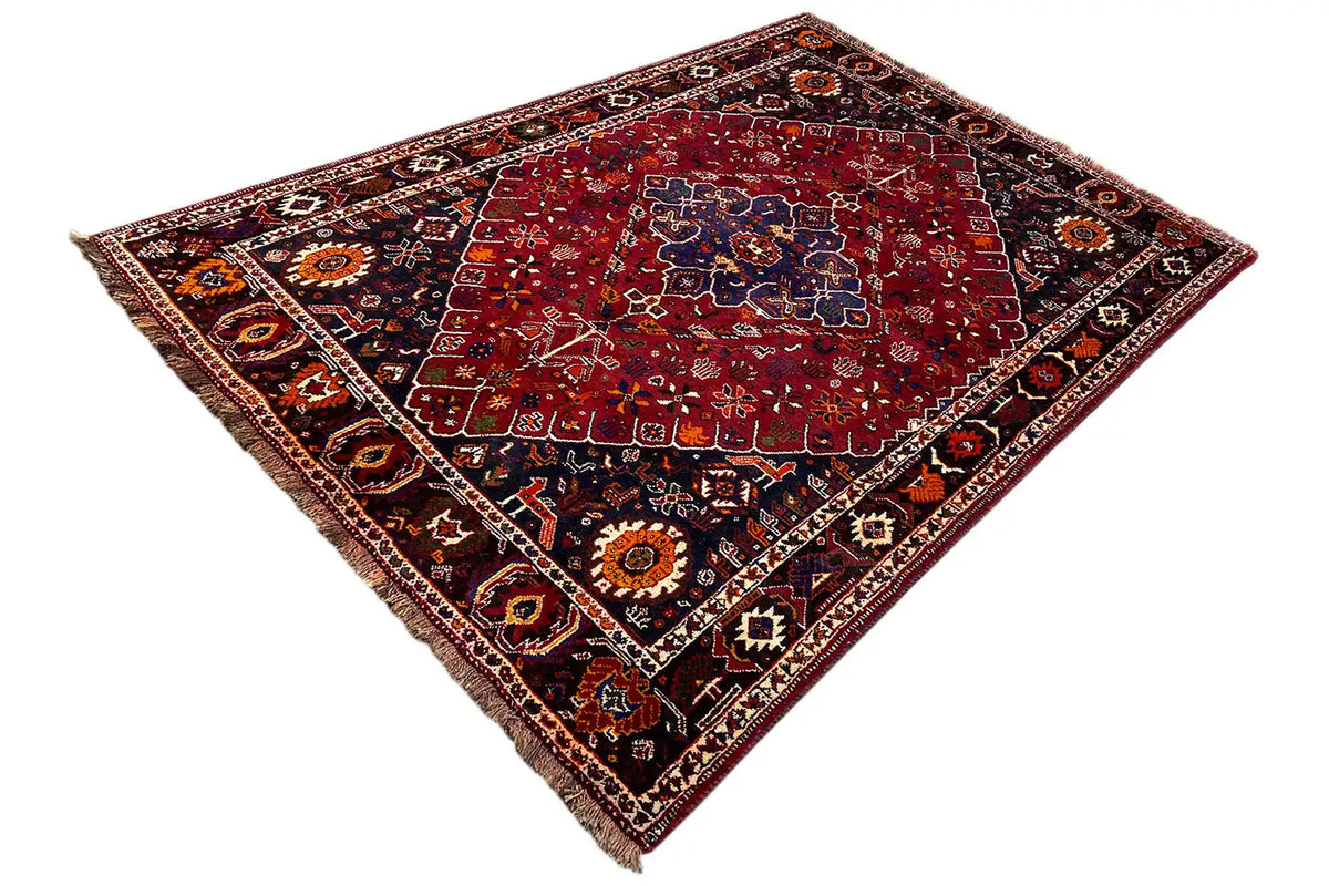 Oriental rug viewed at an angle, red ornamental pattern with a dark border trim