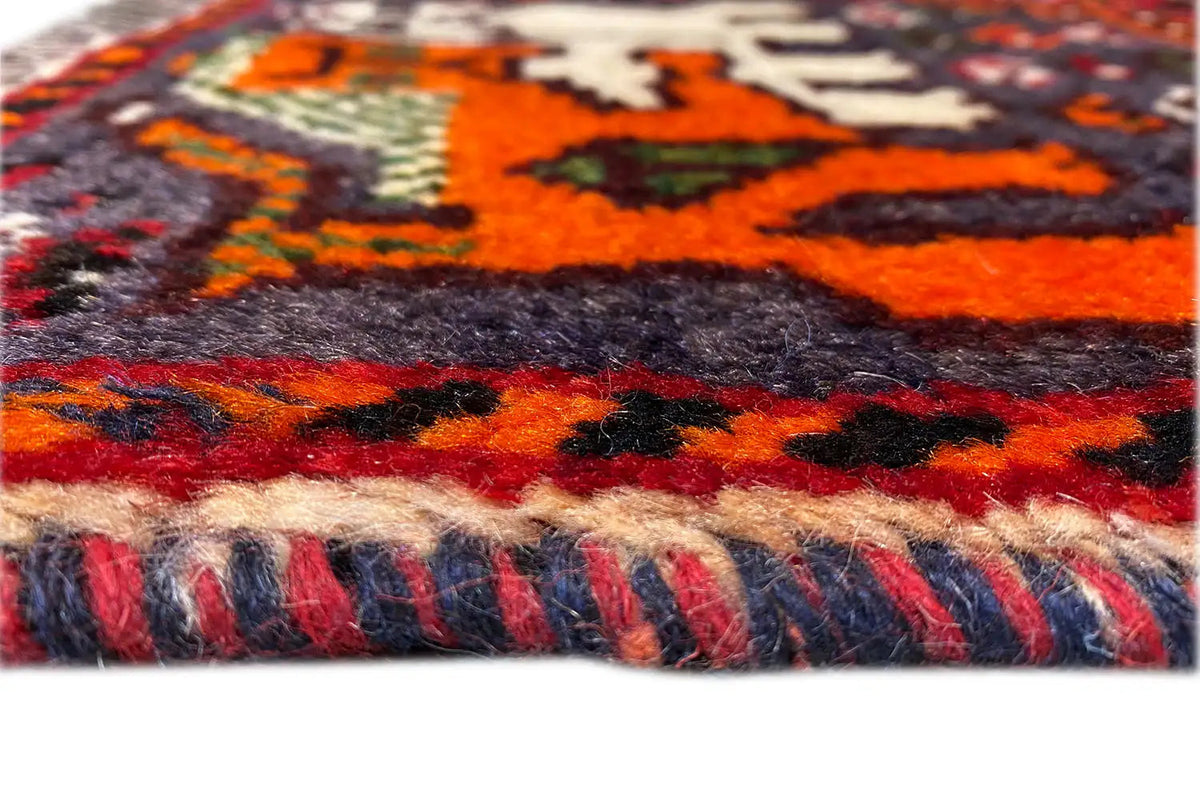 Detail: hand-knotted rug with a multicolored border and fringes along the edge