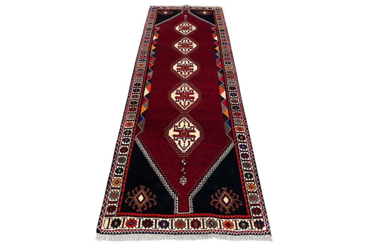 Burgundy runner rug with central diamonds, blue-red borders, and corner motifs