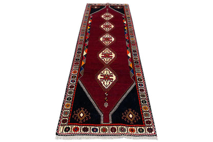 Burgundy runner rug with central diamonds, blue-red borders, and corner motifs