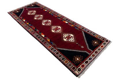 Burgundy runner rug at an oblique angle with an ornamental central stripe
