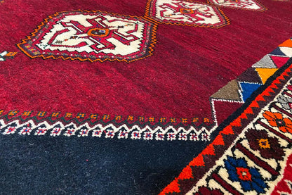 Close-up of the carpet: burgundy surface with ornamental stripes and a dark border