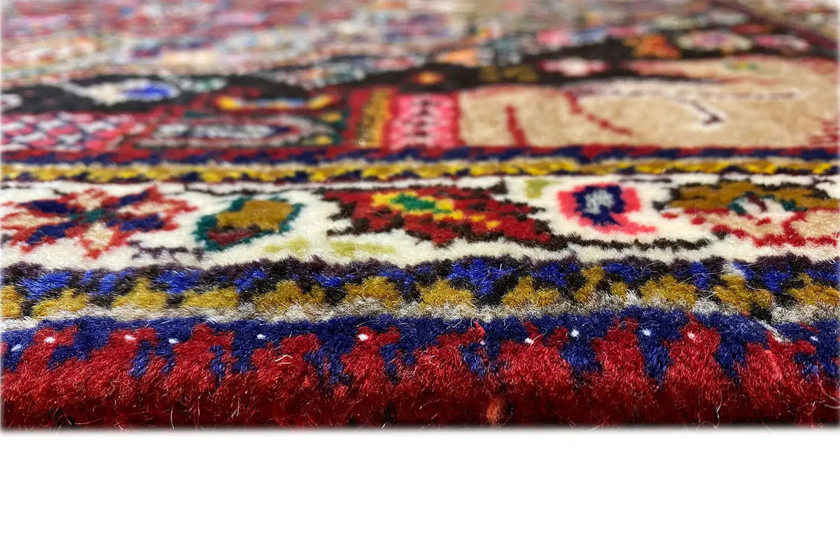 Carpet pile in detail with colorful ornaments and dense pile, red border.