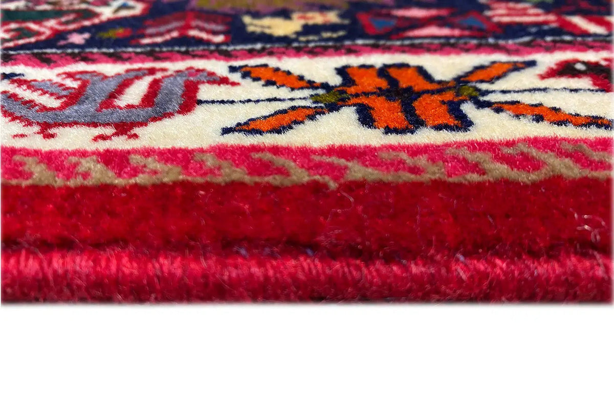 Close-up: red carpet edge with fringes and a colorful ornamental stripe