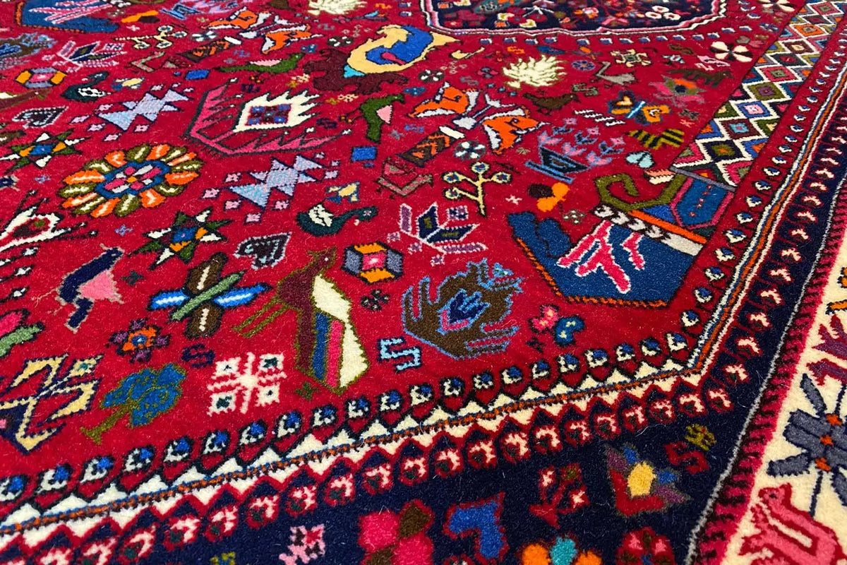 Detailed view of the carpet pattern with colorful figures, floral motifs, and a blue border