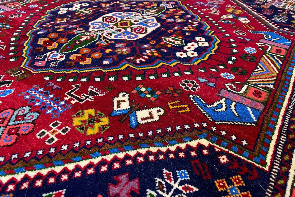 Carpet detail with a red background, blue border pattern, and colorful motifs