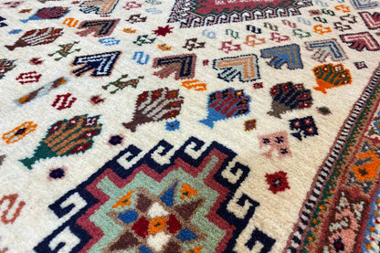 Oriental rug close-up: geometric motifs and border, cream-colored with blue/red