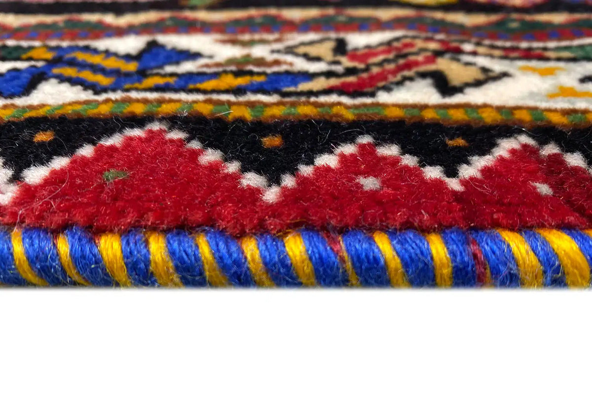 Close-up of carpet edge: multicolored decorative trim with red accents, fringes