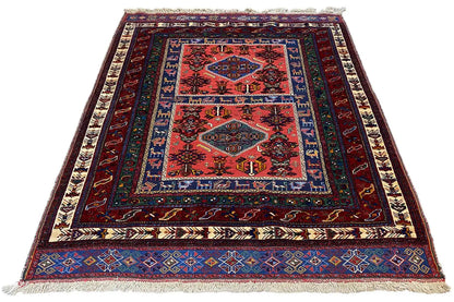 Rug with a red central area and a geometric blue border, fringes on the sides