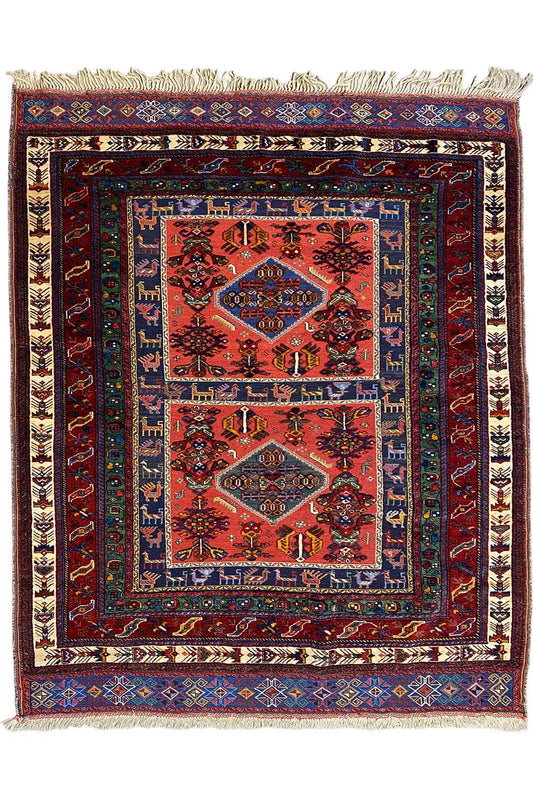 Rug with a red medallion pattern and blue border, with fringes along the edges