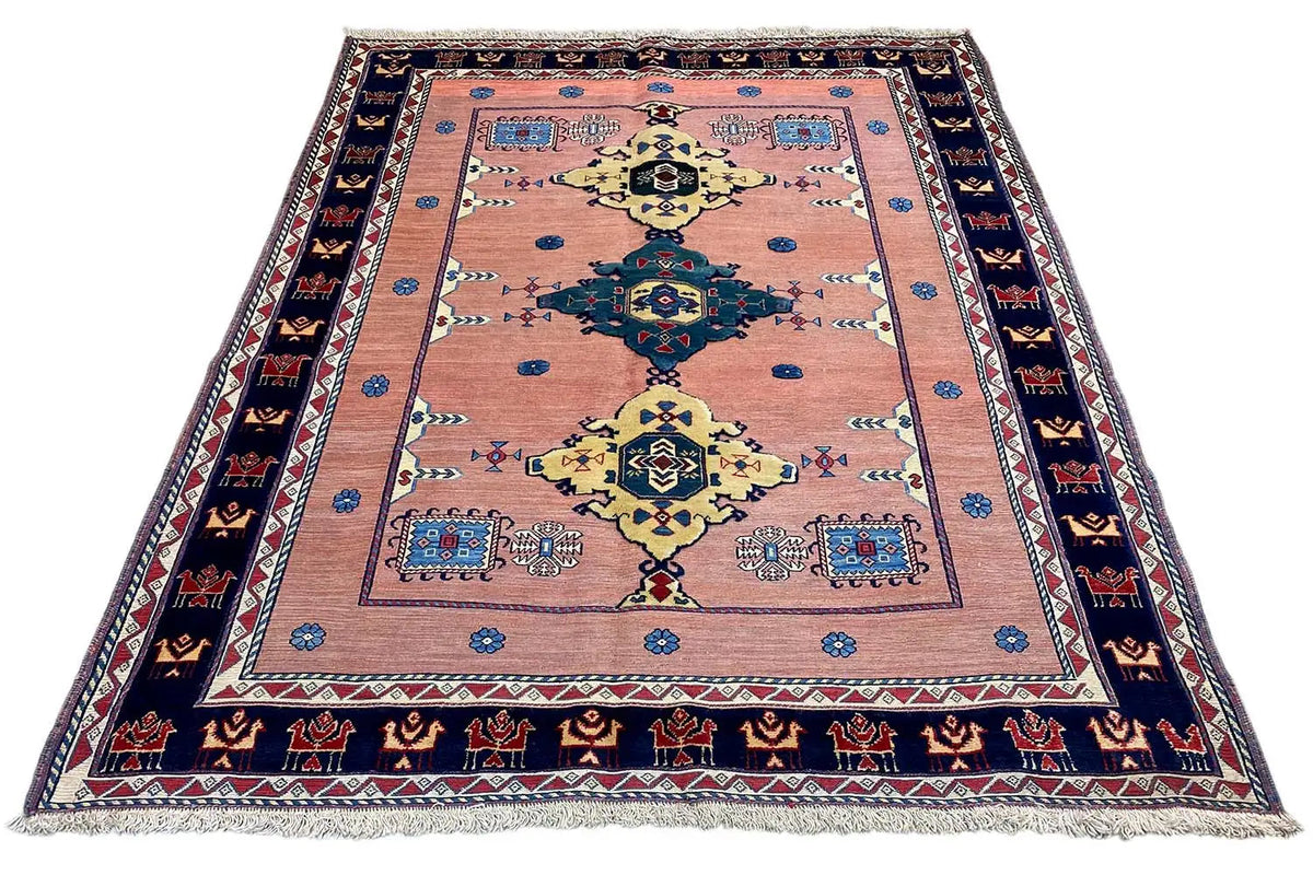 Oriental rug with a large central medallion, pink background, and dark blue border